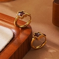 Gedetailleerde macro van gouden oorringen met bruine ster-edelsteen op getextureerde stof - Rode Ster (5999302831659) / Rood