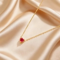 Elegante goldene Halskette mit einem roten herzförmigen Edelstein auf Champagnerseide - Hellrot