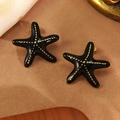 Dettaglio macro di orecchini a stella marina in smalto nero con accenti dorati su tessuto - Stella Marina Nera a Pois (FYD6160EH-black)