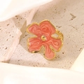 Close-up of golden floral ring with pink marble enamel detail on a soft silk background - Red