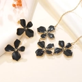Floral jewelry set with black enamel flower necklace and earrings on white fabric background - Black