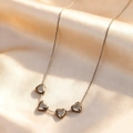 Detailed view of silver heart pendant necklace with four charms on champagne silk fabric - Four Linked Hearts Style (BG002-1) / Silver
