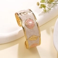 Detailed macro view of sea horse and shell charms on a gold-tone enamel cuff bracelet - Rose Red