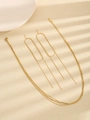 Close-up of minimalist gold layered necklace and geometric tassel earrings on beige surface - Gold Necklace And Earrings Set