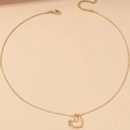 Elegante goldene Herzkette mit minimalistischer Schlangenkette auf beigem Grund - Halskette / Goldfarbene Halskette Mit Hohlherz