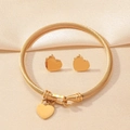 Nahaufnahme eines goldenen Schmucksets mit Herzanhängern und Kabeldraht-Textur - Goldherz Armband und Ohrringe Set