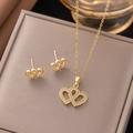 Close-up of gold-plated interlocking heart jewelry set with zircons on leather display - Embracing Hearts Set (8228) / Gold
