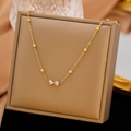 Elegante goldene Schleifen-Halskette mit Herz-Zirkonia-Anhängern auf einer Schmuckbox - Zirkonia Schleife Halskette (Gold)