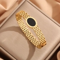 Detailed macro view of gold-plated stainless steel hollow mesh bangle with black oval stone - Gold