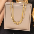Detailed view of layered gold snake chain necklace with round beads on jewelry box - Double Layer Bead Blade Chain Necklace (H1213) / Gold