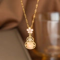 Makroaufnahme der goldenen Kirschblüten-Kürbis-Halskette mit rosa Emaille und orangem Stein - Katzenaugenblume Hulu (9067)
