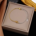 Two-tone gold and silver snake chain bracelet with a central knot design on a jewelry box - Knot Design Two-tone
