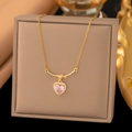 Detail einer Goldhalskette mit rosa herzförmigem Kristallanhänger und Glitzersteinen - Geknotetes Herz (9100) / Gold