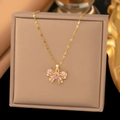 Detail einer goldenen Schleifen-Halskette mit rosa Zirkonsteinen in einer Box - Hohle Schleife (9096) / Gold