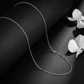 Collier chaîne maille forçat argentée minimaliste sur une surface noire courbée artistique - Chaîne en O Argentée