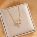 Detailed macro of gold bow pendant necklace featuring pink zircon and micro-pave stones - Gold Pink Diamond Bowknot