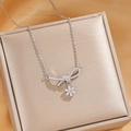 Silver bow necklace with zircon pendant and flower detail on a beige jewelry box - Silver Daisy Bow