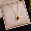 Detail van de paarse zirkoon hanger ketting op een gouden zijden achtergrond - Gelukssteen Waterdruppel (D65)