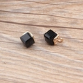 Detailed close-up of water cube crystal charms with gold hollow base on wood - Black