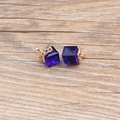 Macro shot of dark blue crystal cube earrings with intricate gold hollow patterns - Sapphire Blue