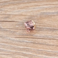 Detailed view of a pink cube crystal pendant with a gold metal base on wood surface - Pink