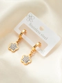Detail of gold stainless steel flower earrings with crystal inlay on beige silk - Zirconia Flower