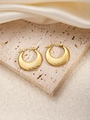 Detailed view of golden twisted hoop earrings on an elegant beige travertine stone surface - U-Shaped E0178 Style