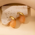 Dettaglio di orecchini a goccia in resina organica placcati oro su sfondo di pietra - Goccia d'Acqua Arancione (E0392)