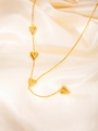 Vue détaillée du collier doré avec pendentifs cœurs 3D sur un tissu de soie - Collier Cœur à Glands