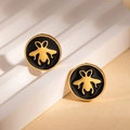Detailaufnahme goldener Bienenohrringe mit schwarzem Emaille auf weißen Stufen - Schwarze Ohrstecker (ZYGE1300)