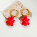 Close-up of golden hoop earrings featuring vibrant red turtle charms on a stone base - Red Turtle