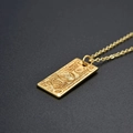 Macro detail of gold hip hop pendant necklace with engraved 100 dollar bill motif - Gold