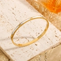Elegant gold stainless steel bangle with white shell inlay and zircon accents on a stone base - Gold