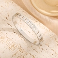 Polished silver twisted twist bangle with sparkling rhinestones on an elegant stone surface - Steel