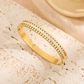 Elegant gold double-row studded bangle with pavé crystals on a textured travertine base - Gold