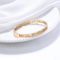 Elegant gold titanium steel open bangle with Greek meander cutout on white ceramic plate - Gold