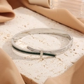 Detail view of silver bow bangle with sparkling rhinestones and green zircon stones - Silver With Green Zircon