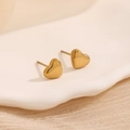 Polished gold heart stud earrings set on a ceramic tray with a warm minimalist aesthetic - Gold Heart Studs
