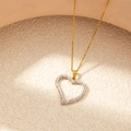 Detail of a golden heart necklace with sparkling clear crystals on a warm textured background - Gold White Zircon Thick Heart