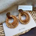 Detail of bohemian round rattan woven earrings with amber resin hooks on burlap background - Brown