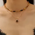 Macro detail of layered beaded necklace with tiger eye stone and gold pendant - Layered Necklace Style
