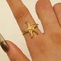 Detailed close-up of a gold starfish ring with a textured 18K gold-plated finish on a finger - Slender Starfish Style (6565) / Gold