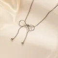Detail of silver snake chain necklace featuring a bow pendant and beaded tassels - Silver Tassel Round Bead