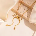 Detail of golden bow necklace with tassel bead on champagne satin and stone background - Gold Tassel Round Bead