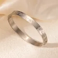 Détail d'un bracelet jonc argenté avec gravure de roses et fermoir de sécurité - Motif de Rose / Or blanc