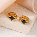 Créoles dorées avec zircon noir en losange sur un présentoir en pierre texturée - Style Losange Noir (1407)