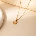 Golden stainless steel Christmas necklace with red hat pendant on a warm beige background - Santa Letter B