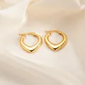 Polished gold heart-shaped hinged hoop earrings on smooth beige silk background - Heart Hoop Earrings 0165