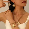 Dettaglio di un set di gioielli vintage a croce dorata con chiusura a barra su modella - Set Collana Bracciale Orecchini Oro