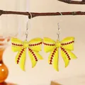 Detail of yellow baseball-style bow earrings made of acrylic on a natural branch - Yellow Softball Style